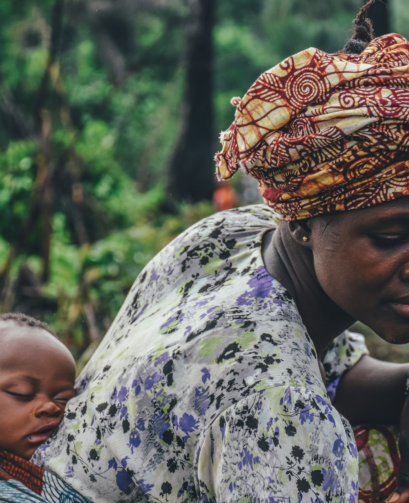 A farmer in a patterned headwrap working a plot of cassava